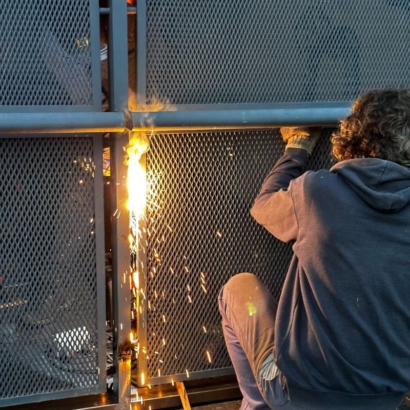 Reparación y soldadura de portón levadizo con malla expandida. Reparación de un portón levadizo con paneles de malla expandida. Se realizó el cambio completo del zócalo inferior y se reforzaron las soldaduras de los paneles para garantizar su estabilidad. Trabajo realizado por HERREELEC.